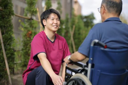 職員が利用者と会話中の庭  