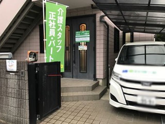 入口と駐車された車 外観 幅広い玄関は、出入りがしやすい設計です。傍に駐車された車が便利さをサポートしています。