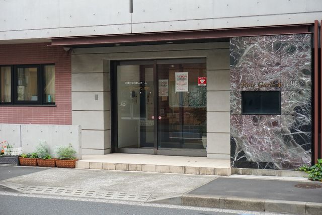 エントランスの外観 玄関 落ち着いた色合いのエントランスは、清潔感があり、歓迎する雰囲気を醸し出しています。職場として、心安らぐ環境が提供されている様子が伺えます。