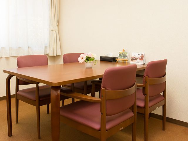 面談用の小部屋 居室 落ち着いた色合いの椅子とテーブルが配置された面談スペースです。自然光をしっかり取り入れられる窓があります。