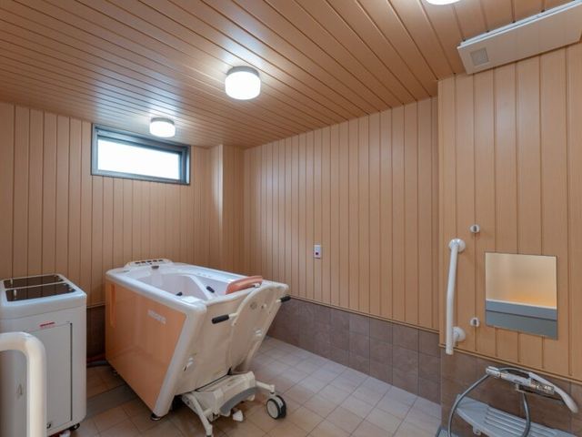 車椅子対応の浴室 浴室   手すりや昇降式の浴槽が見える、介助しやすい浴室です。明るい照明で、落ち着いて入浴支援が行えそうです。