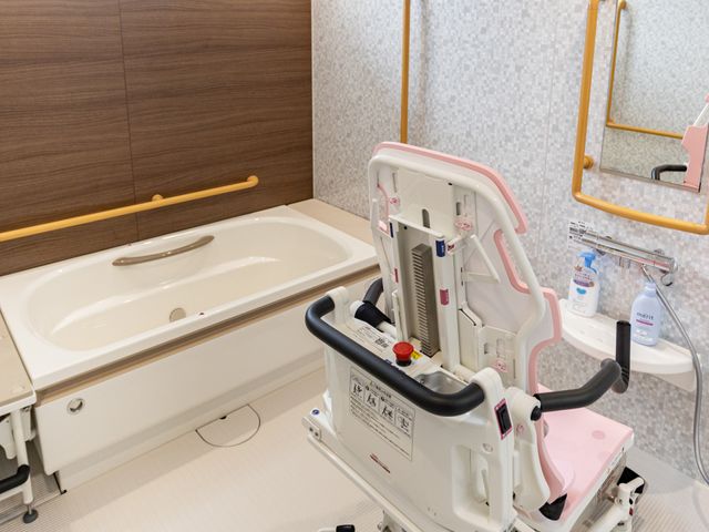 機械浴室 浴室   手すり付きの浴槽と昇降機があり、移乗を支えやすい浴室です。窓から光が入り、明るい環境で入浴介助が行えます。