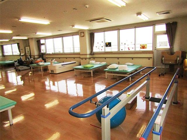 機能訓練室 機能訓練室   明るい窓辺に訓練用ベッドや平行棒が並ぶ、広々とした機能訓練の場です。介助や見守りの動線も確保しやすそうです。