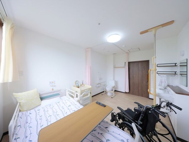 明るい居室 居室   自然光が入る明るい居室です。ベッド周りに手すりや移乗用の備えがあり、車椅子でも使いやすそうです。