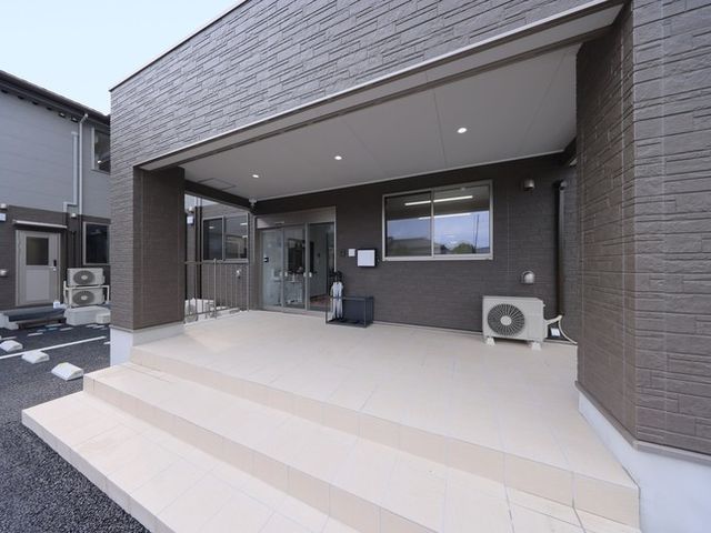 建物正面の玄関先 外観   広いひさしのある玄関前です。段差の少ないアプローチで、出入りしやすい印象です。
