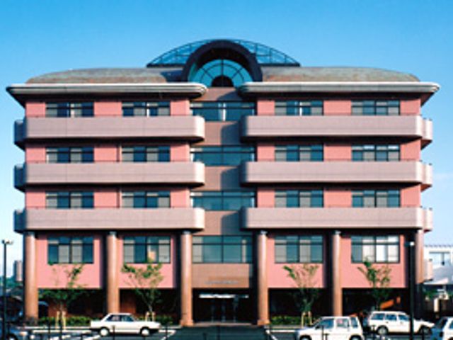 ピンクの建物外観 外観 特徴的なデザインが目を引く建物です。採光を意識した大きな窓が印象的です。