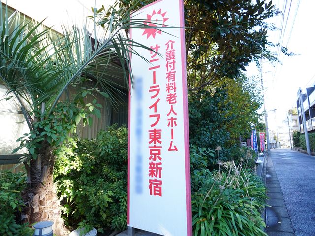 エントランス看板 看板 明るい日差しの中、緑に囲まれた入口標識が目を引きます。