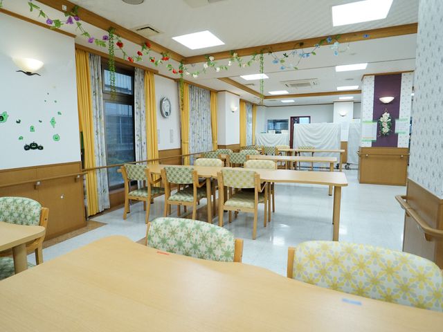 明るい共有スペース 共有スペース ゆとりある座席が並ぶ落ち着いた食堂です。花や緑の装飾が窓辺に添えられ、心地よい雰囲気で食事ができます。