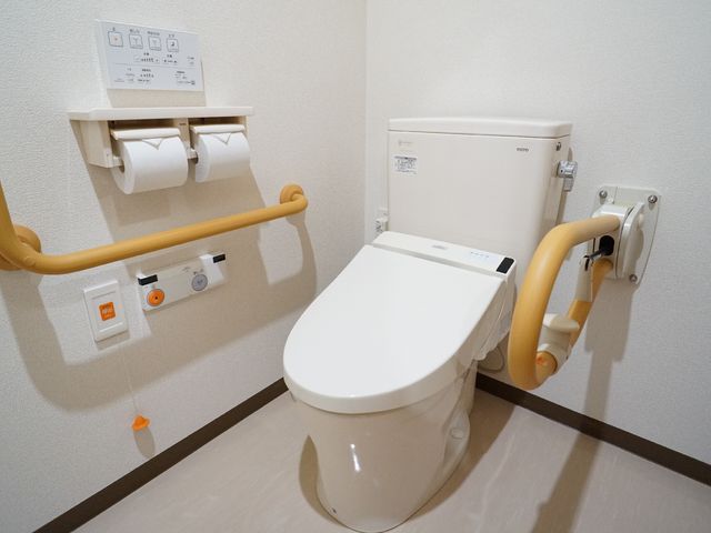 バリアフリートイレの設備 トイレ 安全を考慮したトイレ設備が整っており、手すりや緊急呼び出しボタンも設置されています。利用者の快適さと安心をサポートします。