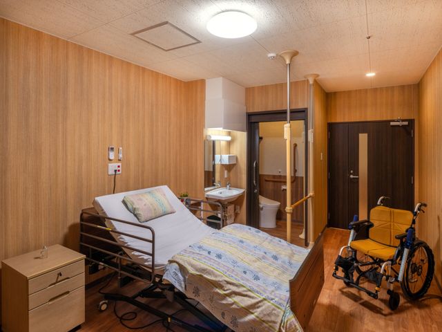 木目調の居室 居室   木目調で落ち着いた雰囲気の居室です。電動ベッドや手すり、洗面台があり、ケアしやすい環境が整っています。
