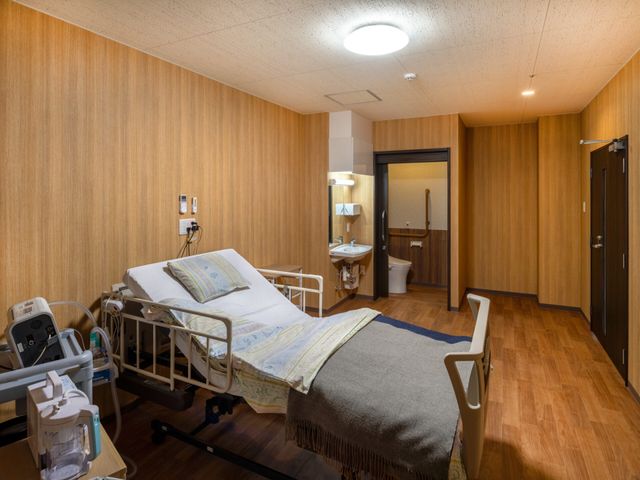 個室の居室 居室   木目調で落ち着いた個室です。ベッド横に洗面台とトイレがあり、動線を確保しやすい設えです。