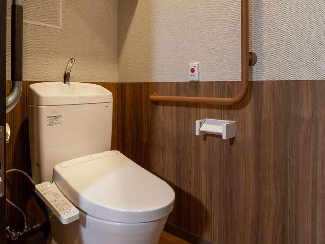 手すり付きトイレ トイレ   手すりが設置された落ち着いた色合いのトイレです。清潔感があり、使いやすさに配慮された空間です。