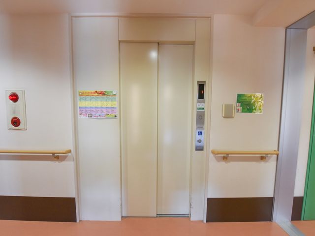 手すり付き廊下のエレベーター エレベーター  安全に配慮された手すりのある廊下に位置するエレベーターは、利用者の移動を円滑に支援します。