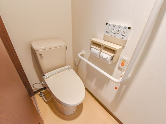 手すり付きのトイレ設備 トイレ  手すりや緊急コールが完備された清潔なトイレ空間です。利用者の安全と快適さを考慮した設計になっております。