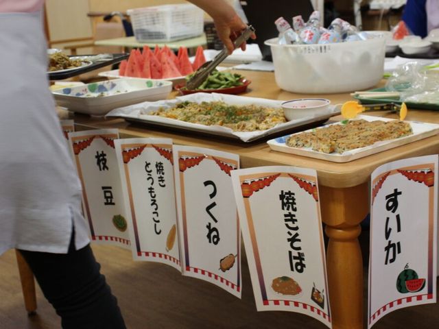 ** 食事メニューの準備風景 ** ダイニングルーム ** 美味しそうな焼きそばや枝豆などが並ぶ、にぎやかな食事の場です。多様な食事をお楽しみいただけます。