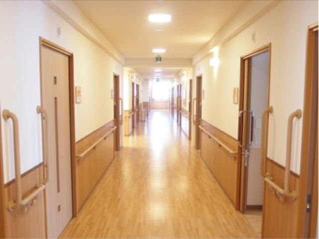 明るい廊下と多数の扉 廊下 手すりが設置されており、床には滑りにくい素材が使用されています。安全に配慮された設計で、快適に過ごせる環境が整っています。