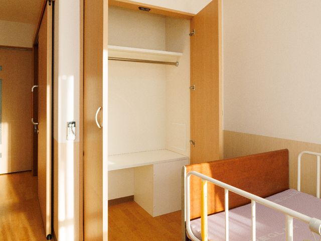 居室のベッドとクローゼット 居室 陽の光が差し込む暖かな雰囲気の個室で、整理整頓しやすい収納スペースがあります。安心してゆったりとお過ごしいただける環境です。
