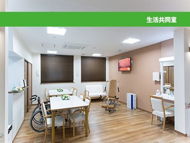 明るい共有スペース 内観   窓から自然光が入り、木目調の床が落ち着いた雰囲気をつくっています。テーブルや椅子がゆったり配置され、くつろぎやすい共有空間です。