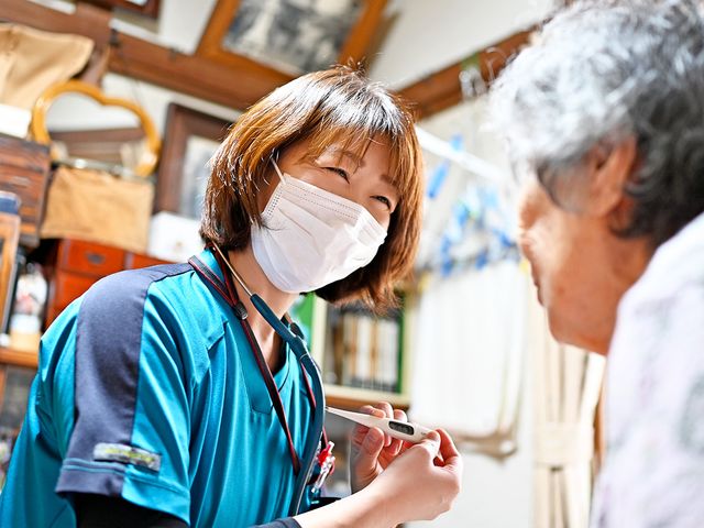 介護スタッフと利用者の会話 スタッフイメージ 優しい表情で手を差し伸べるスタッフが話をする様子です。寄り添うケアが実践されています。