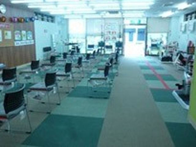 ゆったり配置された椅子の部屋 機能訓練室 椅子が整然と並び、明るい空間でのリハビリや活動に適した環境です。自然光が心地よいです。