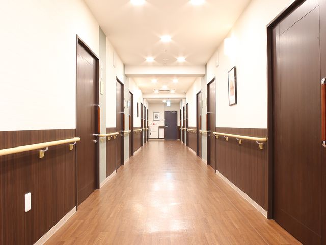 清潔な施設の廊下 廊下 明るく清潔感のある廊下が続いており、静かで落ち着いた雰囲気の中でのお仕事が可能です。手すりも設置されており、安全な環境が整っています。