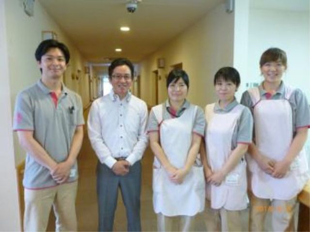 スタッフの笑顔が輝く廊下 スタッフ 温かみのある笑顔で迎えてくれるスタッフチームです。明るい廊下で、心地よいお迎えを期待できます。