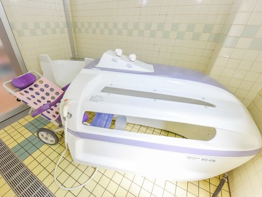 大きなキャスターが付いている入浴用の椅子はリクライニング可能である。タイル張りの床はフラットで移動に配慮されている。
