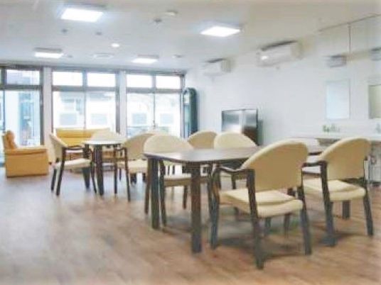 施設の写真 四人掛けのテーブルと椅子、ソファなどが置いてある施設内のリビング・ダイニングスペース