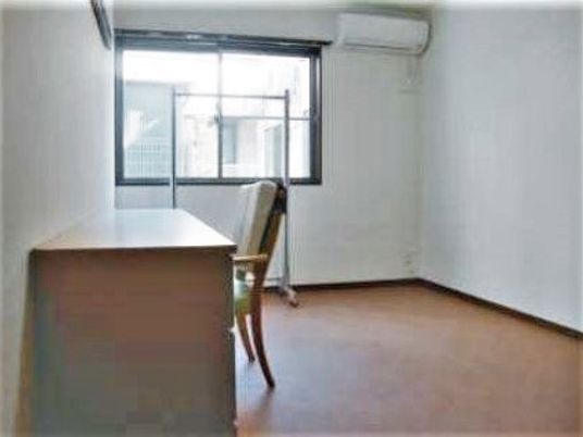 施設の写真 ワンルームタイプの部屋にエアコンとテーブル、いすなどが置いてある様子