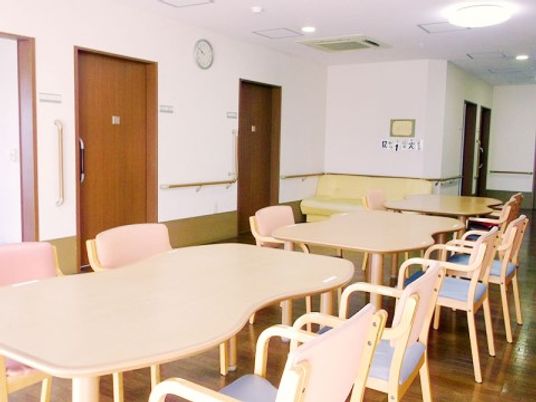 独特な形状をしたテーブルが一列に配置されており、周囲に椅子が並べられている。入居者様の居室が間近にあり、人の集まりやすい空間である。
