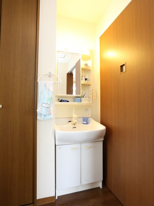 白を基調とした部屋の洗面台には流し台の下や鏡の横に収納スペースがあり、歯ブラシなどの小物を置くことができる。