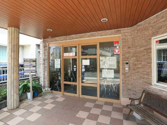 施設の入り口は茶色を基調としたデザインで、自動ドアになっている。入り口脇には休憩できるようベンチが設置されている。