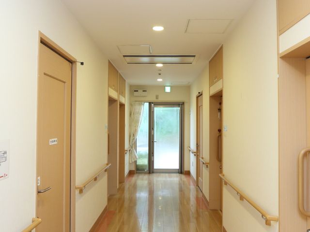 清潔な廊下の風景 きれいに整備された敷地 光をたっぷりと取り入れ、清潔感が漂う廊下は、居心地の良さを感じさせます。手すりが設置されており、どなたでも安心して歩ける設計になっています。
