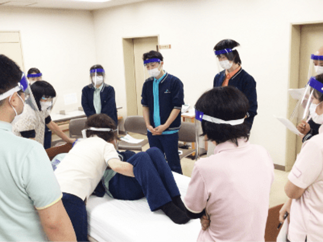 研修中のスタッフの様子 スタッフイメージ スタッフがベッドでの介護技術を学んでいます。互いに学び合う姿勢が見られます。