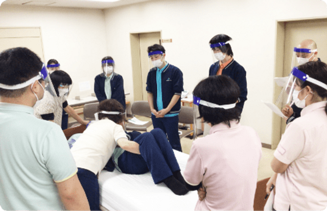 研修中のスタッフの様子 スタッフイメージ スタッフがベッドでの介護技術を学んでいます。互いに学び合う姿勢が見られます。