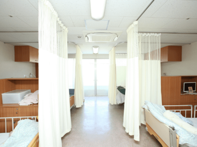 ベッドと明るい部屋 居室 プライバシーに配慮された居室では、個別のスペースが確保されています。自然光が心地よいです。