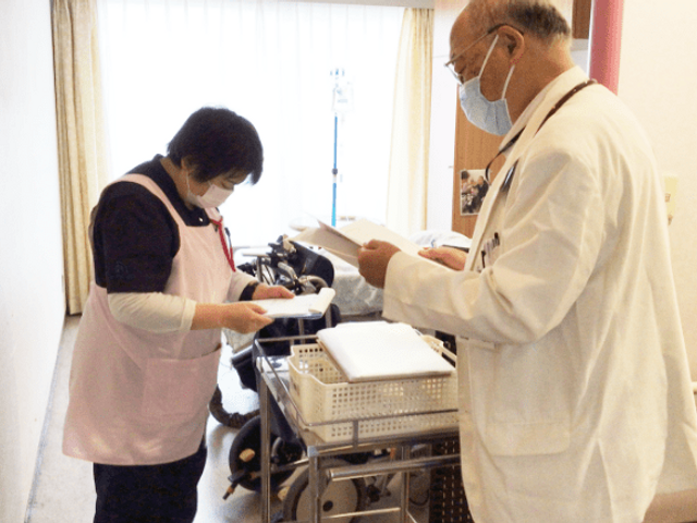 二人のスタッフが話す廊下 廊下   廊下で、医療スタッフが情報を確認し合う様子です。協力し合う姿勢が見られます。