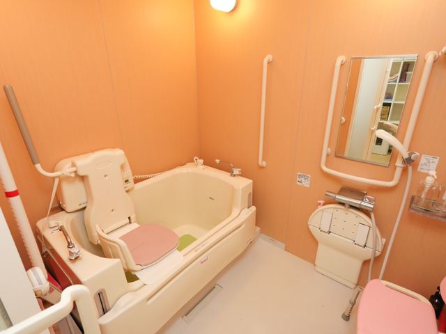 バリアフリー設計の浴室 浴室 手すりが設置された安全な入浴環境が整っており、身体の不自由な方も安心してご利用いただけます。サポートチェアも用意され、自助努力を支える配慮が感じられます。