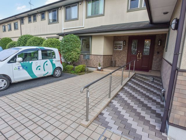 施設のエントランス風景 玄関 手すり付きの坂道が整備された入口は、バリアフリー設計で、利用者の安全な移動を支えています。