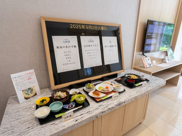テレビと掲示物のロビー 掲示物 メニューが掲示されたエリアでは、本日の食事内容が確認できます。テレビも設置されていて、入所者の方々が情報を得やすい環境です。