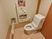 サムネイル 施設の写真 トイレの周りには可動式の手すりと壁に固定された手すりが取り付けられている。トイレットペーパーホルダーは2つ備え付けられている。