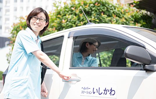 車の前で笑顔のスタッフ