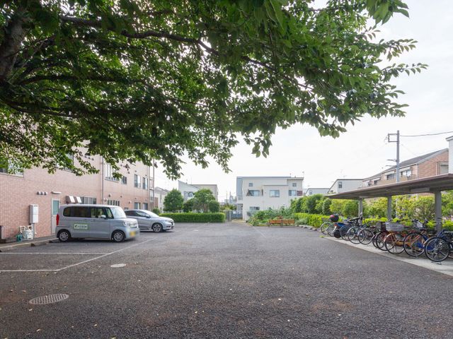 自転車置き場と駐車場の庭 外観 木々に囲まれた駐車場と自転車置き場があります。施設の外観を理解するのに役立ちます。