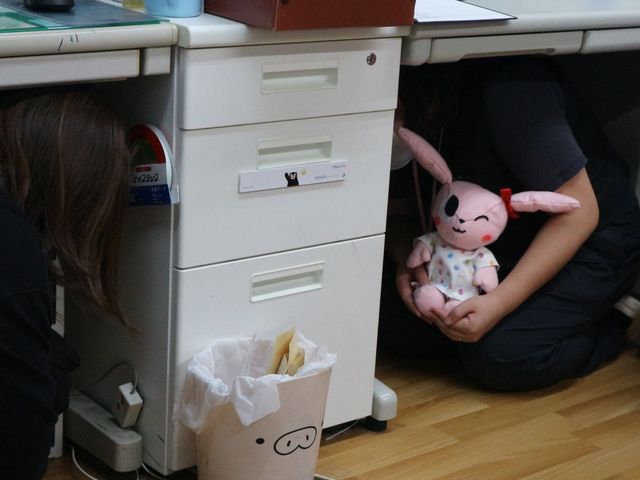 デスク下で何かを探す様子 多目的室 楽しげな雰囲気で、デスク下を活用して活動する場面です。柔軟な発想で創造性を刺激します。