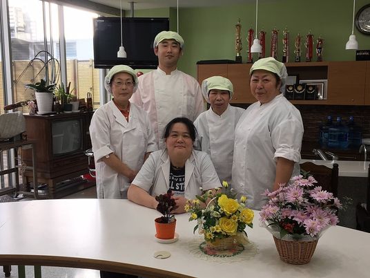 調理服の職員が並ぶ食堂  