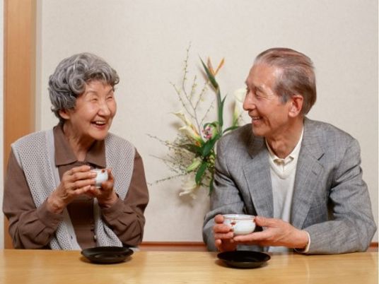 笑顔で茶を飲む高齢者二人