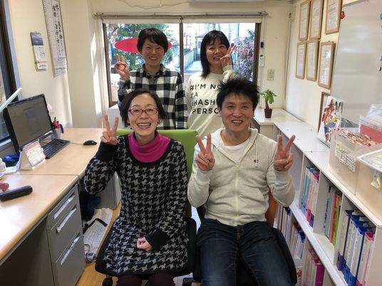 笑顔のスタッフが並ぶ事務室  