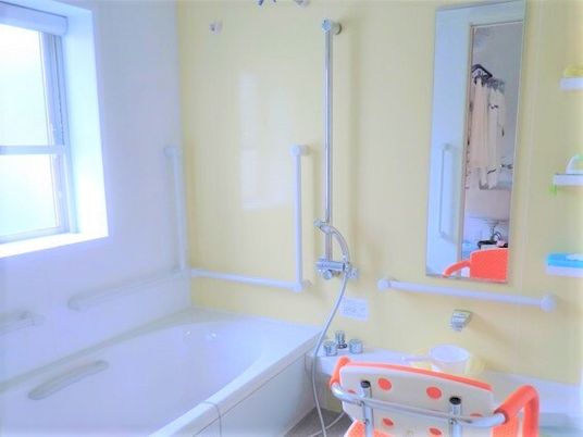 手すりとシャワーチェアがある介護用浴室の様子。小さな浴室の写真