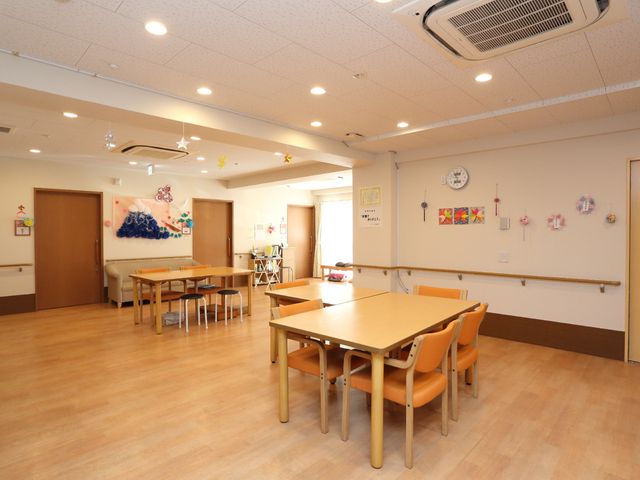 明るい空間の食堂 談話室 ゆったりとしたダイニングで、壁には彩り鮮やかな飾りがあり、明るく家庭的な雰囲気をお楽しみいただけます。ゆとりのある配置で、みなさまの交流の場としてもご利用いただけます。
