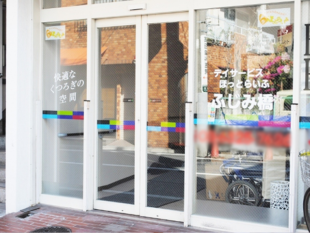 ガラス戸のある入口 エントランス 幅の広いガラス戸が特徴で、陽の光が差し込み明るい雰囲気が感じられます。